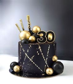 a black and gold birthday cake with decorations