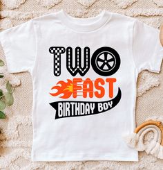 two east birthday boy t - shirt on a bed with some flowers and other items