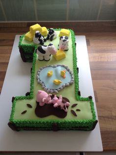 a cake with farm animals on it sitting on top of a white countertop next to a wooden floor