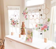 a table with flowers and cards on it in front of two windows, along with other decorations