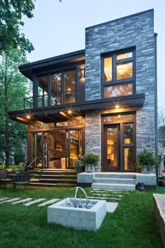 a modern house with an outdoor fountain in the front yard and stairs leading up to it