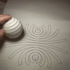 a person holding a ball over a piece of paper with lines drawn on it and circles in the middle