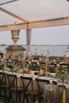 an outdoor dining area with tables and chairs set up for a formal function by the water