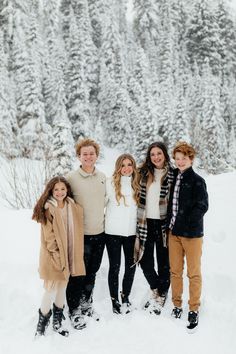 a group of people standing next to each other on top of snow covered ground with trees in the background