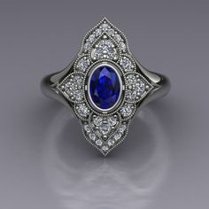 "An oval blue sapphire is set in a bezel in this diamond-studded dinner ring in 14k white gold. The vintage inspired diamond panels are edged with milgrain beading. The top of the ring measures about 20mm at the widest point. Blue Sapphire Dimensions6x4mm EnhancementHeated Carat Weight 0.70 ColorMedium to dark navy blue ClaritySlightly included CutGood PolishGood Diamonds Number22 EnhancementNatural Carat Total Weight0.29 ColorF-G ClaritySI1-2 CutVery Good PolishVery Good This is a custom made item! When you order, we will create a wax model of your ring with our 3D printer. This model is then cast in 14k gold, which is polished and set by hand. This process takes 3-4 weeks, so please allow for this time when ordering if your ring is for a special occasion. Your ring will arrive in a desig Art Deco Oval Sapphire Ring With Accent Stones, Art Deco Oval Diamond Ring With Accent Stones, Classic Oval Sapphire Ring With Diamond Accents, Art Deco Oval Sapphire Ring With Center Stone, Oval Sapphire Ring In Diamond White, Classic Oval Cabochon Sapphire Ring For Anniversary, Luxury Oval Sapphire Ring With Bezel Setting, Oval Sapphire Ring With Rose Cut Diamonds, Classic Oval Sapphire Ring With Rose Cut Diamonds