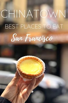 a person holding up a small pastry in front of a building with the words chinatown best places to eat san francisco