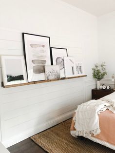 a bedroom with white walls and pictures on the wall