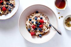 a bowl of oatmeal topped with fruit and nuts on a white plate