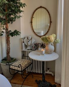 a small table with a mirror on the wall next to a potted plant and candle