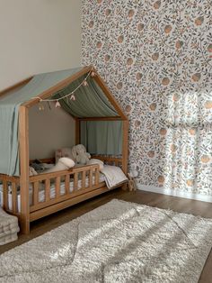 a child's bed in the corner of a room with floral wallpaper and curtains