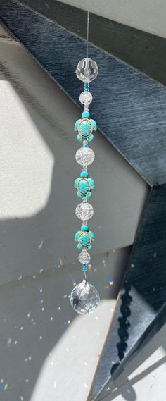 a wind chime hanging from the side of a boat with beads and crystals on it