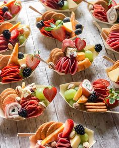 many small bowls filled with different types of snacks on sticks and plates, all arranged in the shape of boats