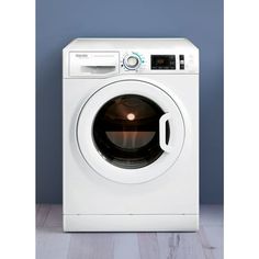 a white washer sitting on top of a wooden floor next to a blue wall