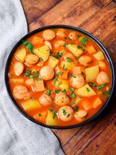 a black bowl filled with stew on top of a wooden table