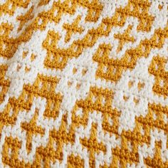 an orange and white crocheted blanket is laying on the floor