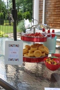 two tiered trays filled with donuts sitting on top of a table next to bowls of fruit