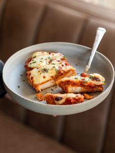 a person holding a plate with chicken parmesan on it