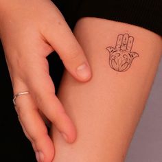 a small hamsa tattoo on the back of a woman's left arm,