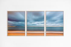 three pictures hanging on the wall in front of a white wall with an ocean view