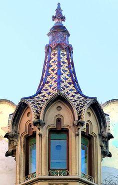 the top of an ornate building with a clock on it's face and windows