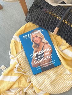 the book swimming against the current by riley cainees is laying on top of a blanket