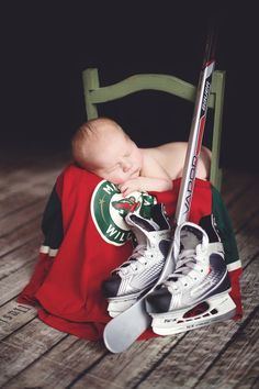 a baby sleeping in a chair with hockey gear