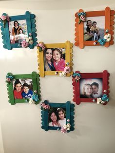 four colorful frames are hanging on the wall with pictures attached to them and flowers in front of them