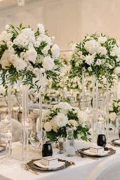 there are many tall vases with flowers in them on the table at this wedding reception