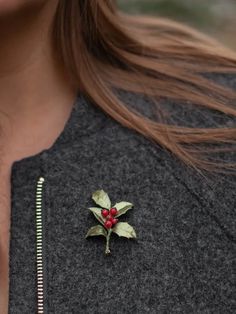 a close up of a person wearing a necklace with a leaf brooch on it