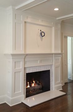 an empty living room with a fire place in the center and wood floors on both sides