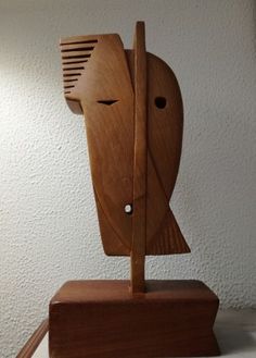 a wooden sculpture with a hair dryer on it's head in front of a white wall