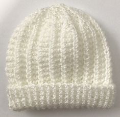 a white knitted hat is shown on a white surface with clippings to the side