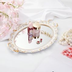 two bottles of nail polish sitting on top of a mirror next to pearls and flowers