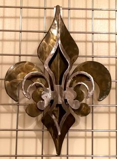 a metal fleur de lis hanging on the side of a wall with white tile