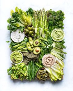 an arrangement of vegetables and dips on a blue surface