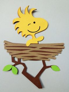 a paper cut out of a child's head sitting on top of a bird nest