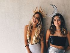 two women standing next to each other in front of a wall with the moon and stars on it