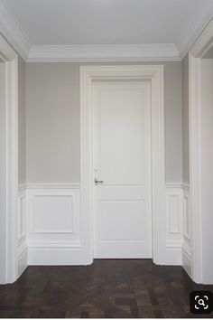 an empty room with wooden floors and white walls, the door is open to reveal another room