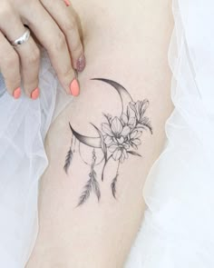 a woman's arm with a flower and crescent moon tattoo on the left side