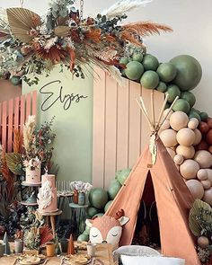 a table topped with lots of cakes and desserts next to a teepee tent