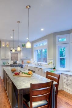 a large kitchen with an island in the middle and two chairs at the counter top