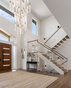 a staircase in a modern home with glass railings and chandelier hanging from the ceiling