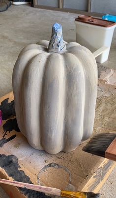 a large white pumpkin sitting on top of a wooden table next to paint and brushes