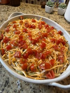 a casserole dish with tomatoes, cheese and onions in it on a kitchen counter