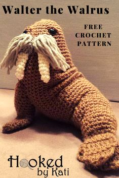 a crocheted sea lion stuffed animal sitting on the ground with its mouth open