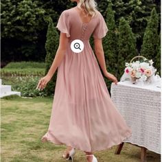 a woman in a pink dress standing next to a table