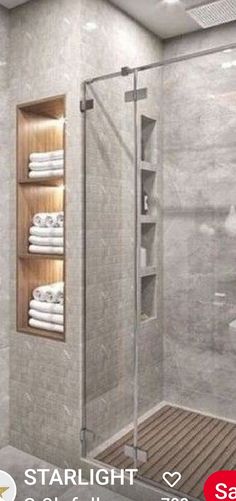 a walk in shower sitting next to a wooden shelf with white towels on top of it