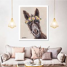 a painting of a donkey with flowers in its hair is hanging on the wall above a couch