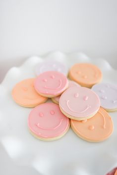 a white plate topped with cookies covered in frosting and smiley face cutouts on top of each other