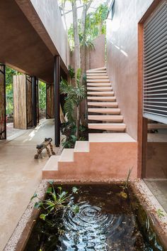 a person sitting on the ground in front of a house with stairs and water feature